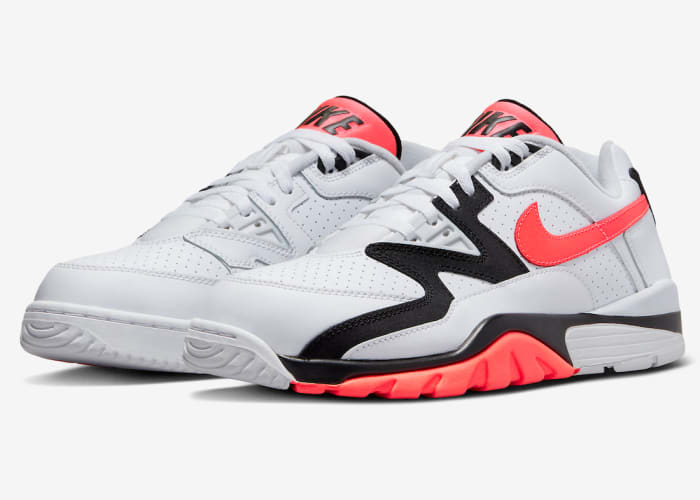 Side view of white, black, and orange Nike training shoes.